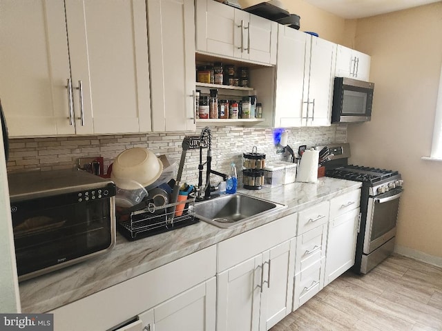 6553 N Smedley St, Philadelphia, PA 19126 - kitchen with stainless steel range with gas cooktop, decorative backsplash, white cabinets, a sink, and black microwave
