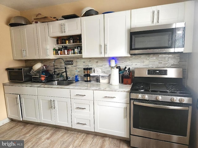 6553 N Smedley St, Philadelphia, PA 19126 - kitchen featuring appliances with stainless steel finishes, a sink, decorative backsplash, and white cabinets