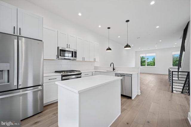 6522 Magnolia St, Philadelphia, PA 19119 - kitchen featuring appliances with stainless steel finishes, a peninsula, a kitchen island, light countertops, and backsplash