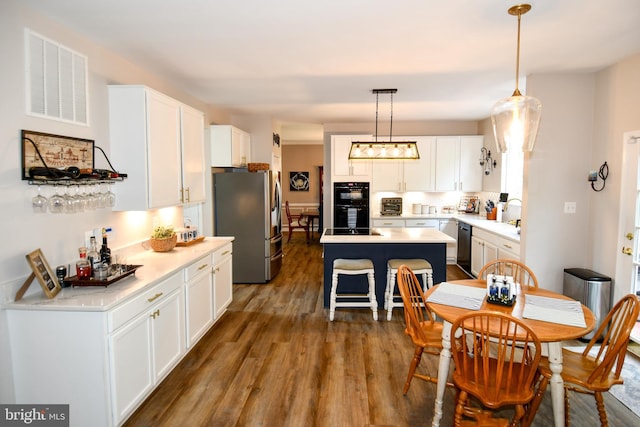 9111 Dartford Pl, Bristow, VA 20136 - kitchen with stainless steel fridge, wood finished floors, white cabinetry, a center island, and light countertops