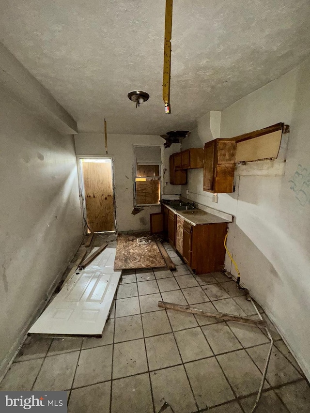 328 S Payson St, Baltimore, MD 21223 - kitchen with brown cabinets, a sink, a textured ceiling, and light tile patterned floors