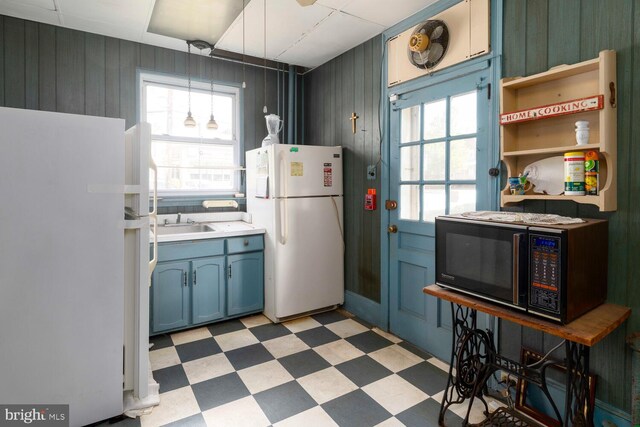 559 Righter St, Philadelphia, PA 19128 - kitchen with freestanding refrigerator, black microwave, light floors, blue cabinets, and wooden walls