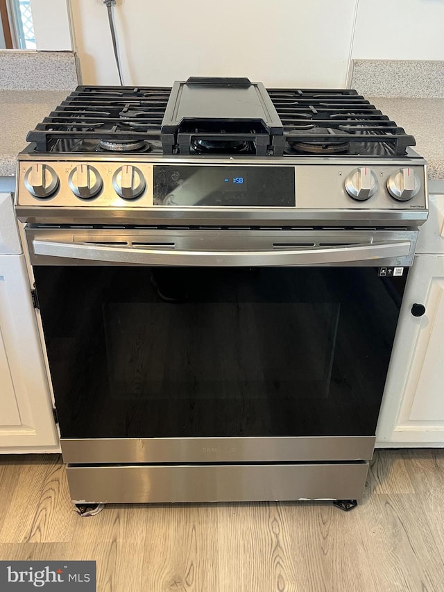 517 S Wayne St, Lewistown, PA 17044 - kitchen view of stainless steel range with gas stovetop, white cabinetry, and light wood-type flooring
