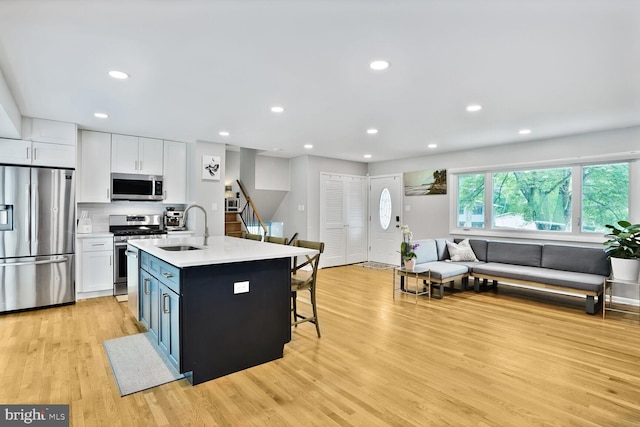 11106 Byrd Dr, Fairfax, VA 22030 - kitchen with appliances with stainless steel finishes, a sink, light wood finished floors, white cabinetry, and open floor plan