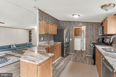 129 Trailway Rd, Middle River, MD 21220 - kitchen with washer / clothes dryer, stainless steel appliances, light wood-style floors, a sink, and a peninsula