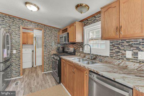 129 Trailway Rd, Middle River, MD 21220 - kitchen featuring stainless steel appliances, washer / clothes dryer, a sink, ornamental molding, and light wood-style flooring