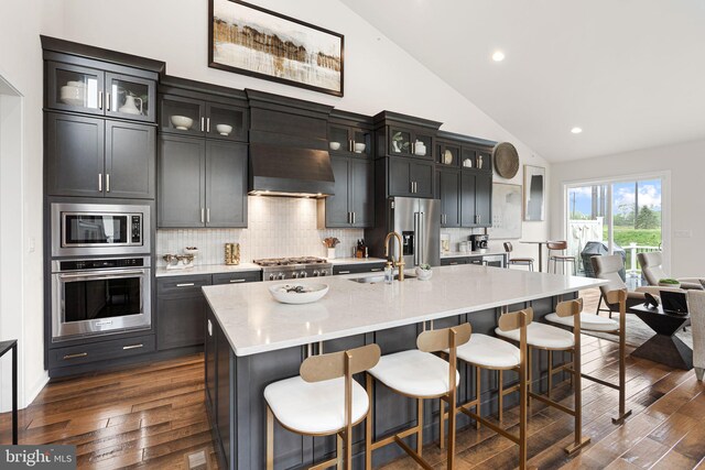 71 Tamarack Cir, Eagleville, PA 19403 - kitchen featuring stainless steel appliances, a sink, wall chimney exhaust hood, dark wood finished floors, and an island with sink