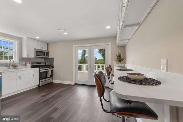 1508 W 36th St W, Baltimore, MD 21211 - kitchen with appliances with stainless steel finishes, french doors, white cabinetry, dark wood-style flooring, and decorative backsplash