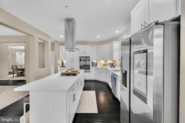 12116 Elmwood Dr, Brandywine, MD 20613 - kitchen featuring appliances with stainless steel finishes, island exhaust hood, white cabinets, a center island, and tasteful backsplash