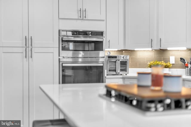 12116 Elmwood Dr, Brandywine, MD 20613 - kitchen with double oven, light countertops, white cabinets, and backsplash