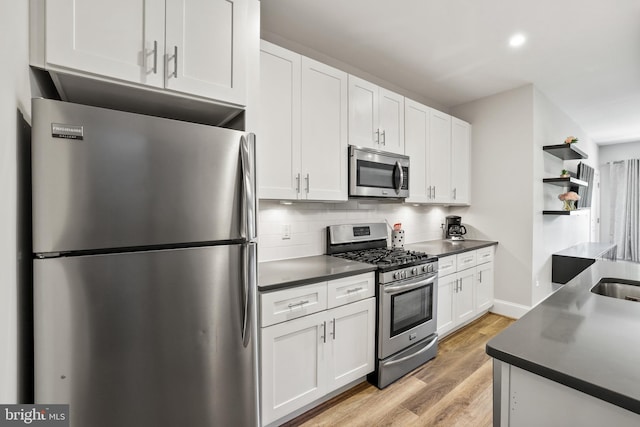 2221 M St NE Unit Ph1, Washington, DC 20002 - kitchen with appliances with stainless steel finishes, dark countertops, light wood-type flooring, white cabinetry, and decorative backsplash