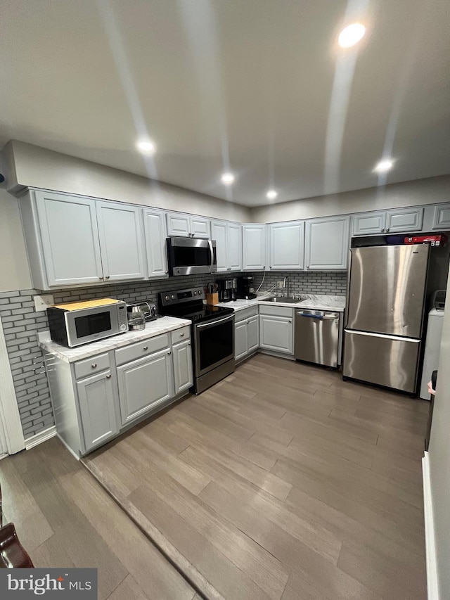 120 N Baylor Dr, Sterling, VA 20164 - kitchen with stainless steel appliances, light countertops, tasteful backsplash, light wood finished floors, and a sink