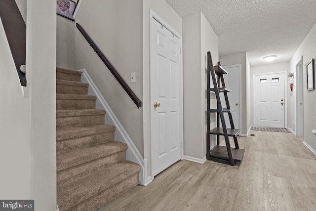 74 Haverford Ct, Hillsborough, NJ 08844 - hallway with light wood-style flooring, stairway, baseboards, and a textured ceiling