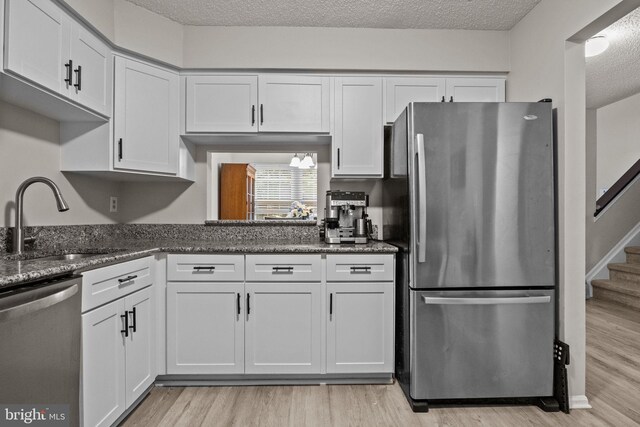 74 Haverford Ct, Hillsborough, NJ 08844 - kitchen featuring appliances with stainless steel finishes, white cabinetry, light wood-style floors, and a textured ceiling