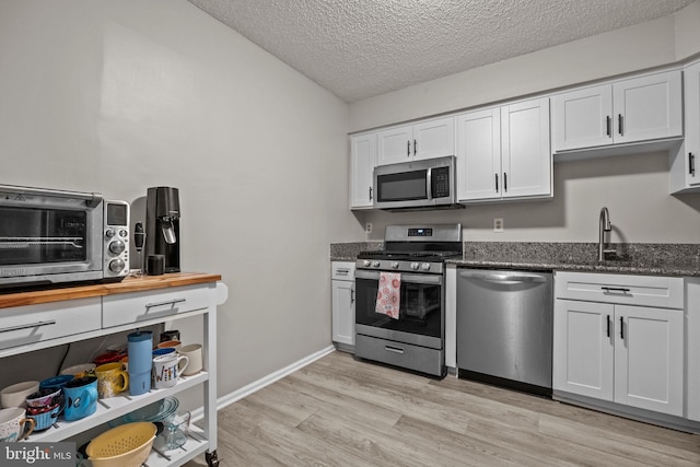 74 Haverford Ct, Hillsborough, NJ 08844 - kitchen featuring appliances with stainless steel finishes, a sink, a textured ceiling, light wood-type flooring, and white cabinets
