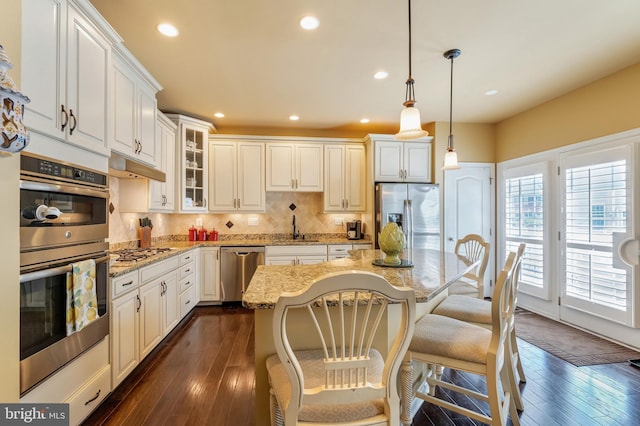 23412 Berkeley Meadows Dr, Ashburn, VA 20148 - kitchen with appliances with stainless steel finishes, a sink, under cabinet range hood, decorative backsplash, and light stone counters