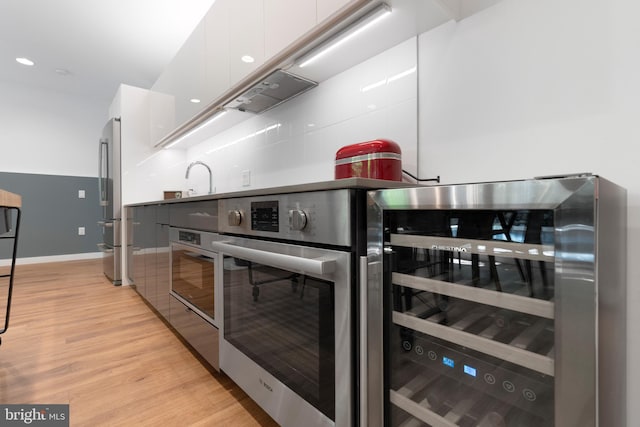 57 N St NW Unit 134, Washington, DC 20001 - kitchen with wine cooler, stainless steel appliances, white cabinets, light wood-type flooring, and modern cabinets