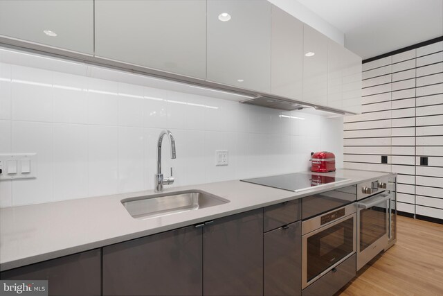 57 N St NW Unit 134, Washington, DC 20001 - kitchen with oven, black electric stovetop, a sink, and tasteful backsplash