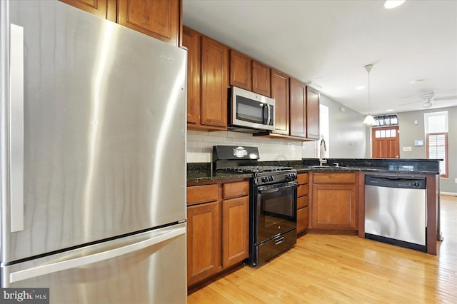 1225 W Cross St, Baltimore, MD 21230 - kitchen featuring appliances with stainless steel finishes, a sink, a peninsula, light wood-type flooring, and brown cabinets