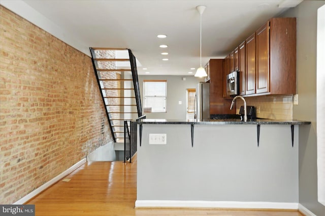 1225 W Cross St, Baltimore, MD 21230 - kitchen with appliances with stainless steel finishes, light wood finished floors, dark stone counters, a peninsula, and a kitchen bar