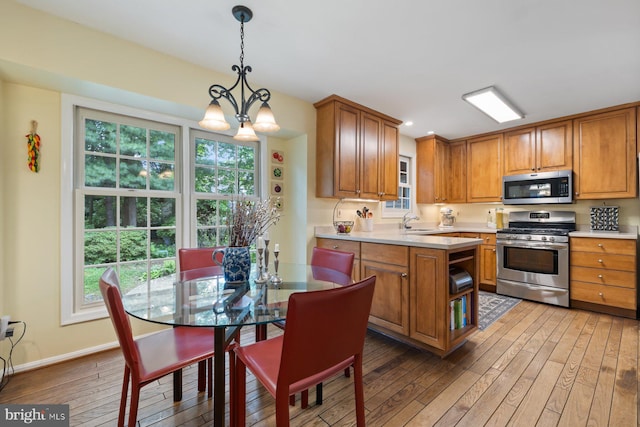 9300 Olivia Pl, Burke, VA 22015 - kitchen featuring stainless steel appliances, light wood-type flooring, brown cabinetry, a sink, and light countertops
