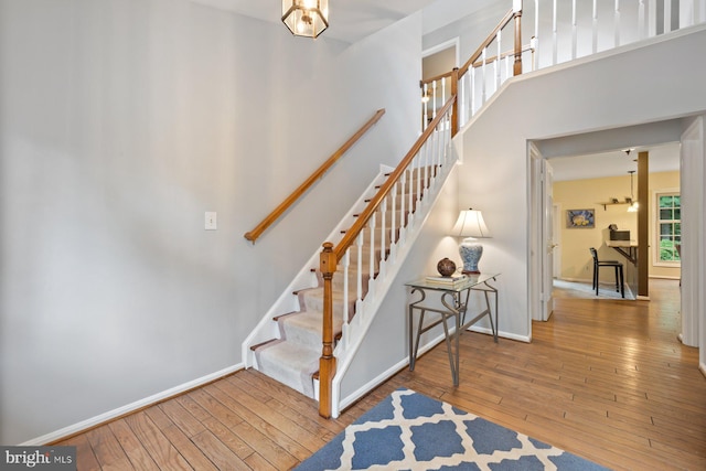 9300 Olivia Pl, Burke, VA 22015 - stairs with hardwood / wood-style floors, baseboards, a high ceiling, and a chandelier