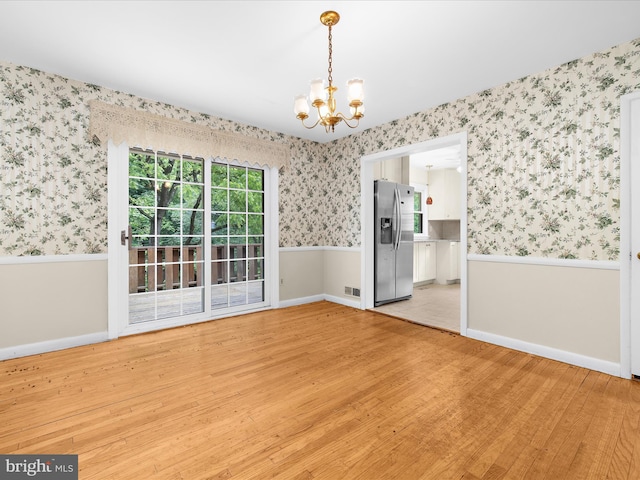 6748 Glenkirk Rd, Baltimore, MD 21239 - unfurnished dining area featuring wallpapered walls, a chandelier, light wood-style flooring, a wainscoted wall, and baseboards