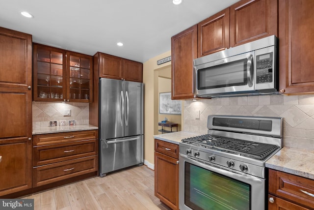 4515 Willard Ave Unit 610S, Chevy Chase, MD 20815 - kitchen featuring stainless steel appliances, decorative backsplash, light wood-style flooring, recessed lighting, and glass insert cabinets