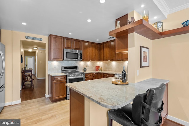 4515 Willard Ave Unit 610S, Chevy Chase, MD 20815 - kitchen featuring stainless steel appliances, a peninsula, light stone counters, light wood-style flooring, and decorative backsplash