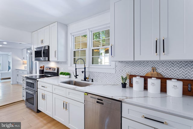 347 Clarks Tract Tract, Keswick, VA 22947 - kitchen featuring appliances with stainless steel finishes, light stone countertops, white cabinetry, light wood finished floors, and tasteful backsplash