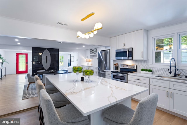 347 Clarks Tract Tract, Keswick, VA 22947 - kitchen with stainless steel appliances, light stone countertops, white cabinetry, a chandelier, and decorative backsplash
