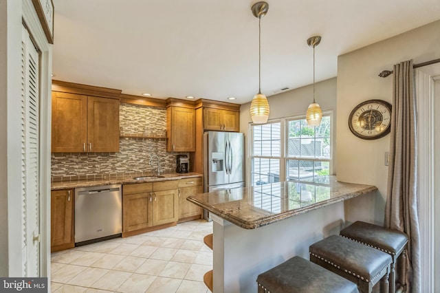 2 E Park Rd, Newtown, PA 18940 - kitchen with stainless steel appliances, brown cabinetry, a breakfast bar, tasteful backsplash, and pendant lighting
