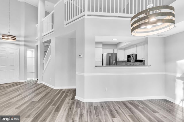 1334 Garden Wall Cir Unit 407, Reston, VA 20194 - unfurnished living room with a towering ceiling, baseboards, stairway, wood finished floors, and a chandelier