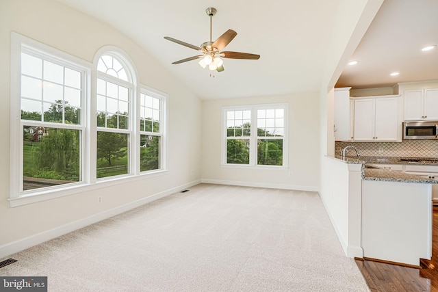 7425 Signal Hill Rd, Manassas, VA 20111 - kitchen with stainless steel appliances, stone counters, vaulted ceiling, white cabinetry, and decorative backsplash