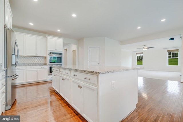 7425 Signal Hill Rd, Manassas, VA 20111 - kitchen with appliances with stainless steel finishes, a kitchen island, light wood-type flooring, decorative backsplash, and white cabinets