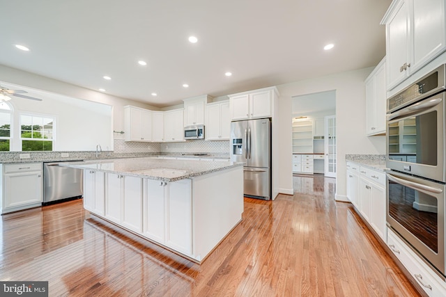 7425 Signal Hill Rd, Manassas, VA 20111 - kitchen with appliances with stainless steel finishes, light wood-style flooring, white cabinets, a kitchen island, and recessed lighting
