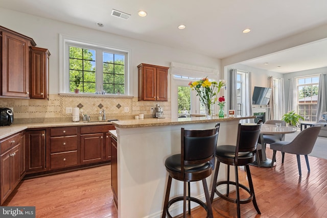 42735 Macauley Pl, Ashburn, VA 20148 - kitchen with a kitchen breakfast bar, light wood-style floors, decorative backsplash, a sink, and recessed lighting