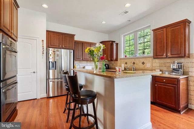 42735 Macauley Pl, Ashburn, VA 20148 - kitchen featuring stainless steel appliances, light wood-style floors, a kitchen breakfast bar, backsplash, and recessed lighting