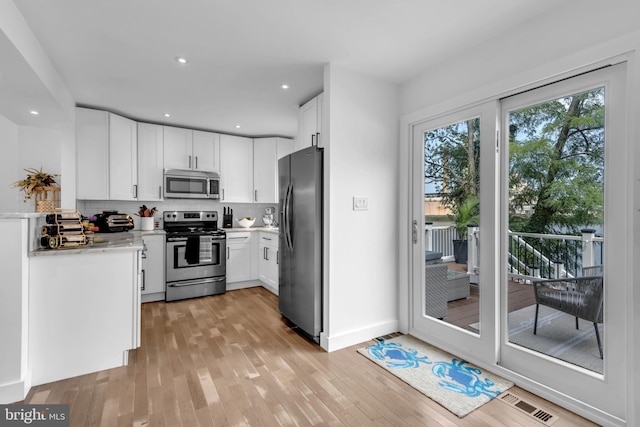 1328 Cox Cv, Stoney Beach, MD 21226 - kitchen featuring appliances with stainless steel finishes, decorative backsplash, white cabinetry, light countertops, and light wood-style floors