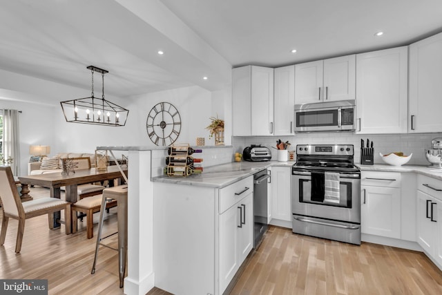 1328 Cox Cv, Stoney Beach, MD 21226 - kitchen featuring appliances with stainless steel finishes, decorative backsplash, light wood-style flooring, white cabinetry, and recessed lighting