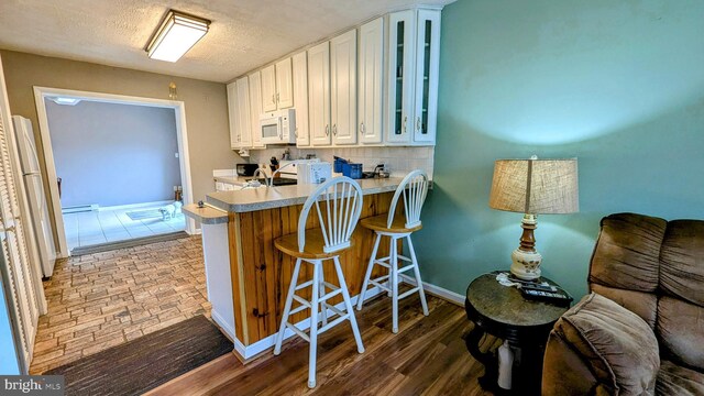 12 Rogers Cir, Newark, DE 19702 - kitchen with white microwave, glass insert cabinets, white cabinets, light countertops, and baseboard heating