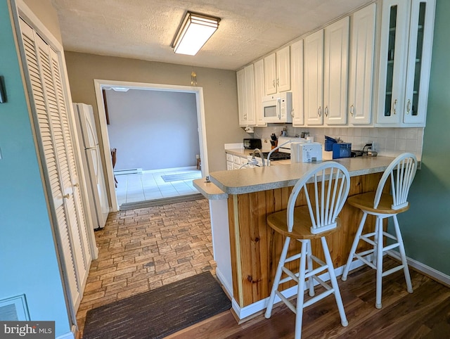 12 Rogers Cir, Newark, DE 19702 - kitchen featuring white appliances, white cabinets, baseboard heating, glass insert cabinets, and light countertops
