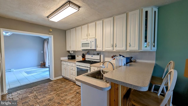 12 Rogers Cir, Newark, DE 19702 - kitchen featuring white appliances, white cabinets, a breakfast bar area, a peninsula, and light countertops