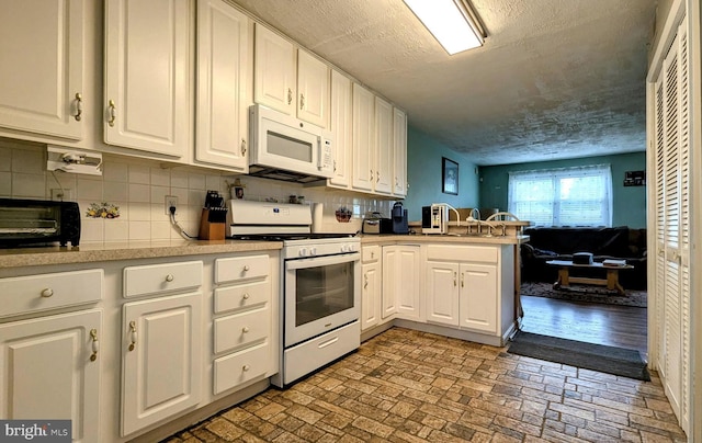 12 Rogers Cir, Newark, DE 19702 - kitchen featuring white appliances, white cabinetry, a peninsula, brick patterned flooring, and light countertops