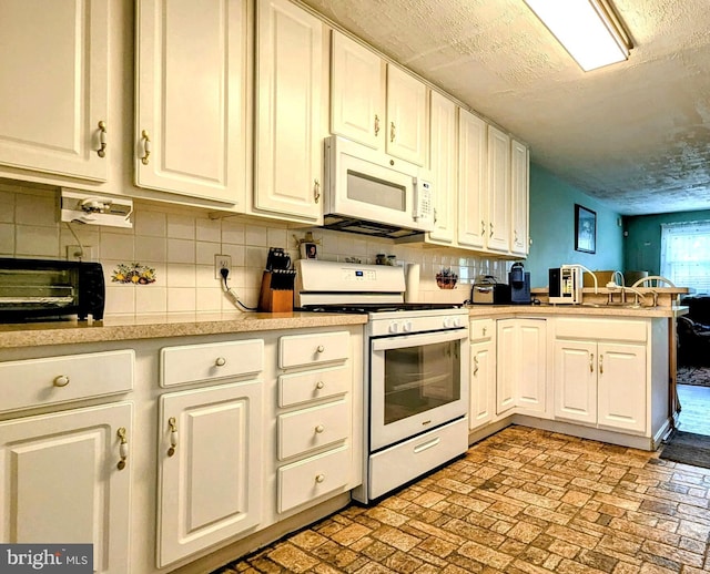 12 Rogers Cir, Newark, DE 19702 - kitchen with white appliances, a peninsula, light countertops, brick patterned floors, and backsplash