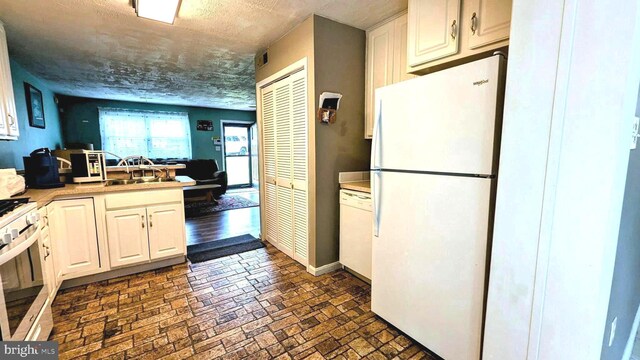 12 Rogers Cir, Newark, DE 19702 - kitchen with white appliances, brick patterned flooring, light countertops, baseboards, and white cabinets