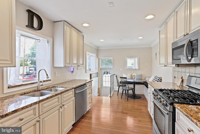 1201 Cooksie St, Baltimore, MD 21230 - kitchen featuring stainless steel appliances, light stone counters, light wood-style floors, crown molding, and backsplash