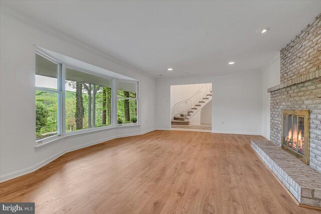 711 E Center St, Nesquehoning, PA 18240 - unfurnished living room with healthy amount of natural light, a brick fireplace, light wood-style floors, baseboards, and crown molding