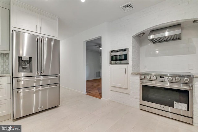 711 E Center St, Nesquehoning, PA 18240 - kitchen with appliances with stainless steel finishes, wall chimney exhaust hood, a ceiling fan, backsplash, and light tile patterned floors