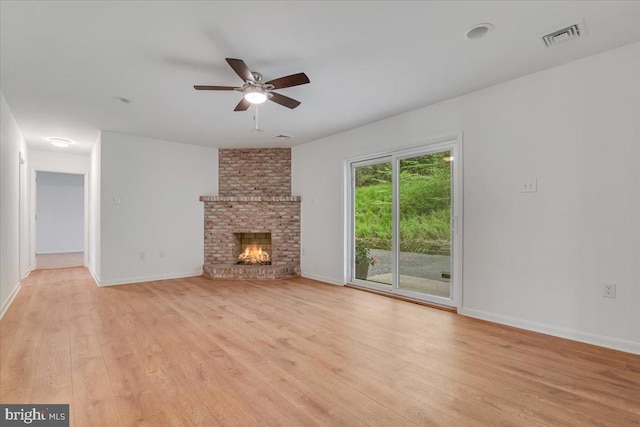 711 E Center St, Nesquehoning, PA 18240 - unfurnished living room with light wood-type flooring, ceiling fan, baseboards, and a brick fireplace